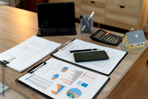 Financial Analyst Reviewing Property Investment Reports and Data Charts on Modern Home Office Desk