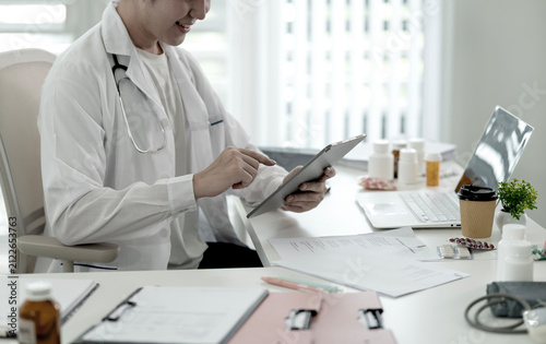 Male Doctor Using Digital Tablet Reviewing Patient Medical Records in Modern Clinic Office