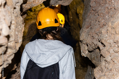 Rear view of a tourist group wearing safety helmets inside a rocky cave