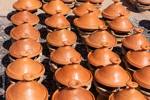 Traditional Moroccan tagine pots made from clay displayed and ready for sale at an roadside outdoor pottery market in Morocco.
