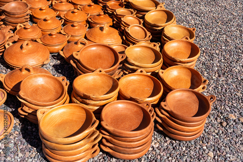 Traditional Moroccan tagine pots and plates made from clay displayed and ready for sale at an roadside outdoor pottery market in Morocco.