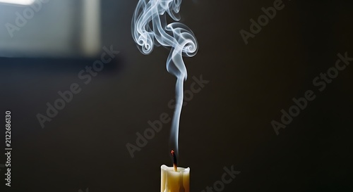 White smoke rising from a freshly extinguished candle against dark background