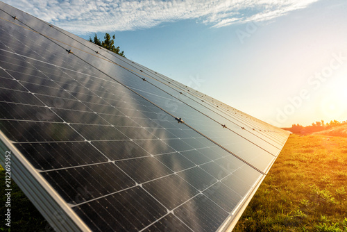 Low angle view of massive solar panels rows under bright sky