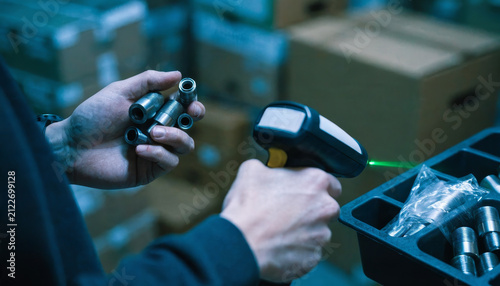 Close up of hands holding metal parts, scanning barcode with handheld scanner in warehouse, industrial inventory management process, efficient, organized, focused