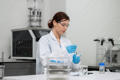 Konstfotografi Expert female scientist mixing chemical solution in beaker with stirring rod at modern laboratory for pharmaceutical formulation, advanced medical research, and commercial biotechnology development