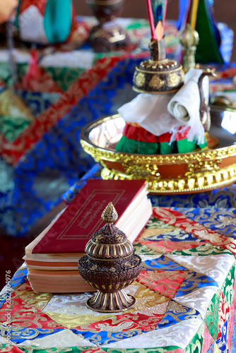 Obraz na płótnie Tibetan ritual set: repoussé bronze box with lid, oblong liturgical text (pecha), and gilded tray with bumpa, arranged on ceremonial brocade; Vajrayana Buddhism