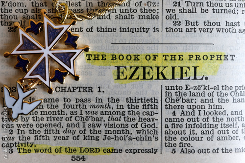 Foto A Protestant Huguenot cross made of gold with blue enamel, featuring a verse from Ezekiel highlighted in an antique Bible