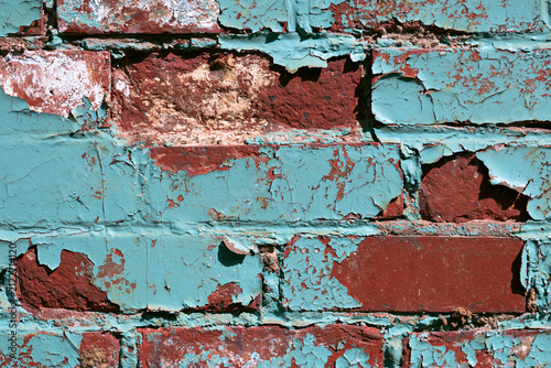 Close up texture of aging red brick wall with cracked blue paint