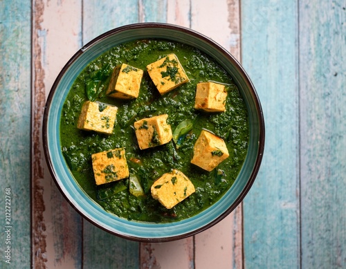 vibrant spinach curry with tofu cubes in rustic top view of palak paneer or