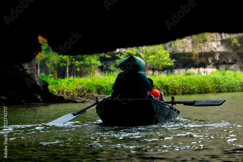 A person is boating on a river, passing through a cave in the Hoa Lu region. Tam Coc, Vietnam.