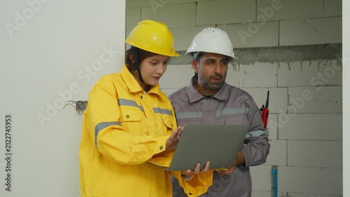Construction worker safety helmet inspection blueprint laptop teamwork building site planning project home inspector building site safety helmet worker review plan laptop construction wall renovation