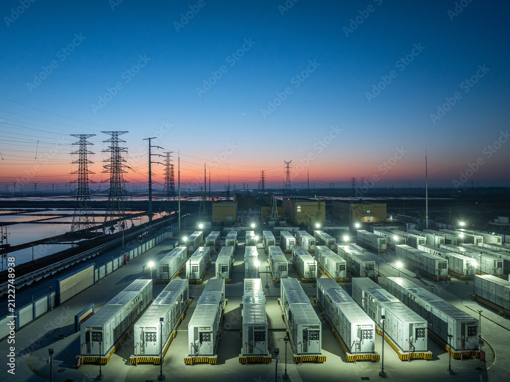 Fototapeta premium Energy storage power station with battery container arrays illuminated at dusk