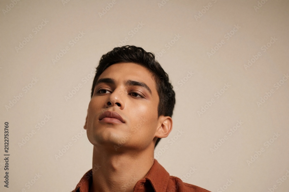 Fototapeta premium Male Model Portrait with Luxury Makeup and Terracotta Shirt against Beige Background