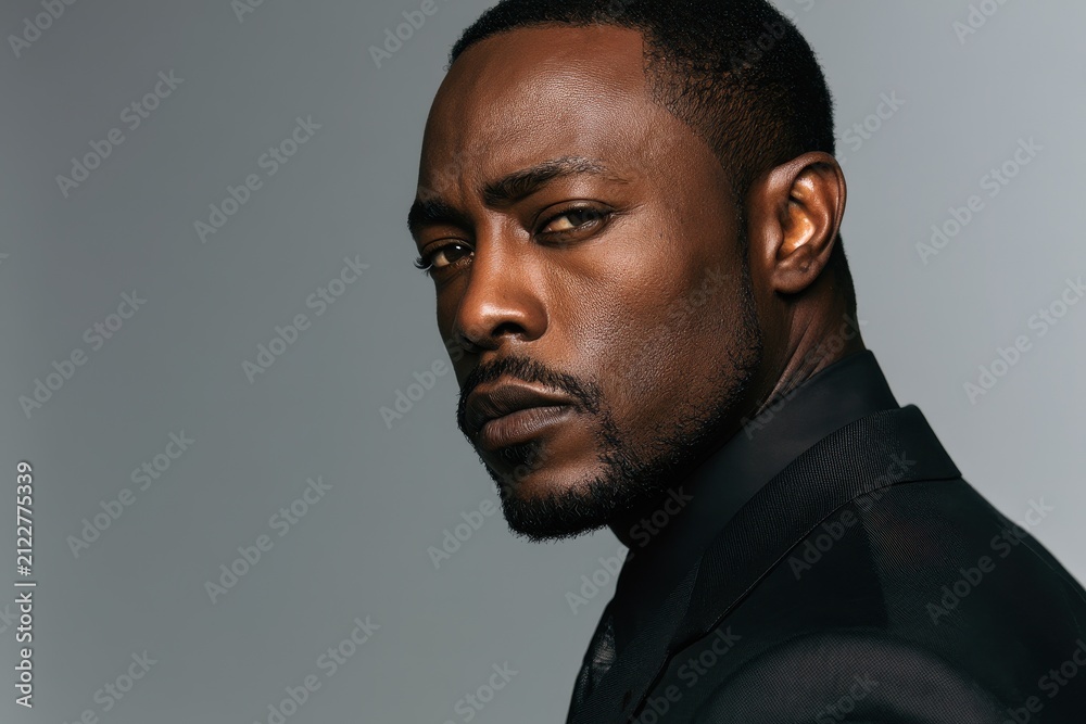 Obraz premium Side profile headshot of a poised man wearing a modern tailored suit with a neutral gray background
