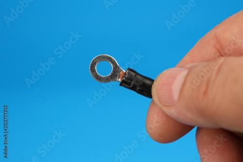 The hand holds an electric copper wire with a metal tip of a round shape. 