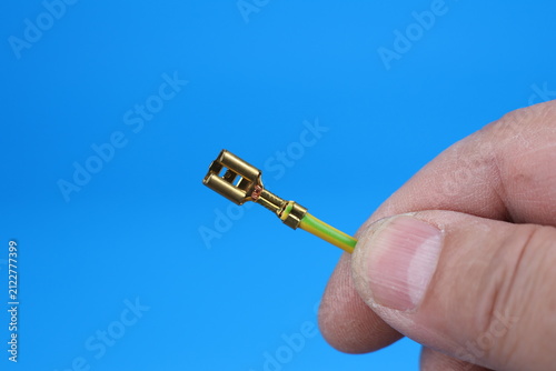 The hand holds an electric copper wire with a metal tip of a round shape. 