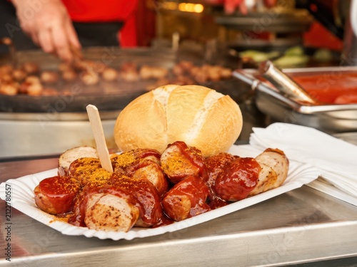 Currywurst mit würziger Sauce und Brötchen am Volksfeststand – Der beliebte deutsche Imbiss wird frisch vom Grill serviert und steht für deftigen Genuss und Tradition.