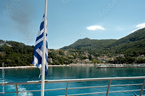 Ferry with Greek flag on blue water, Kefalonia mountains