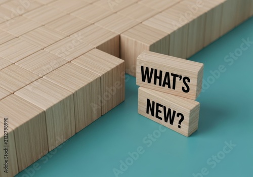 Wooden blocks spelling out whats new arranged on a teal surface, symbolizing new beginnings, updates, or fresh information