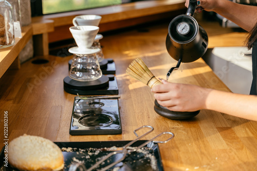 Bild auf Leinwand Skilled barista preparing matcha with bamboo whisk and hot water at specialty co