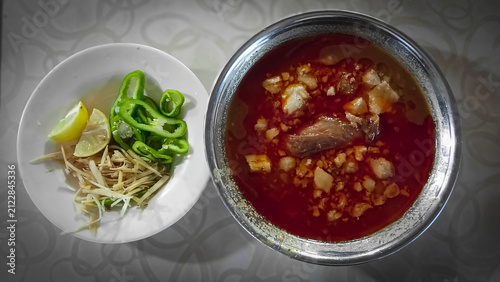 Traditional Pakistani food Nihari with ginger lemon and green chili garnish in a metal bowl overhead view flat lay