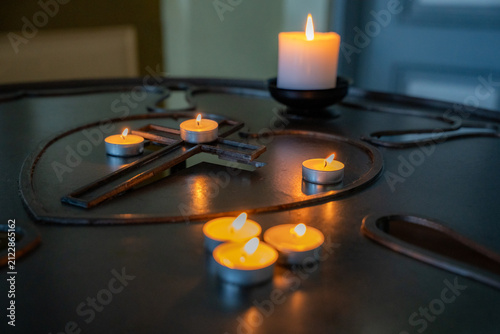 Fotografie Burning candles arranged around a Christian cross on a church candle stand