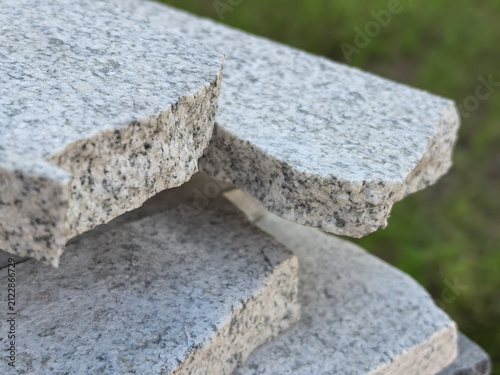 Fotografie Close up of stacked granite slabs with rough edges on green background