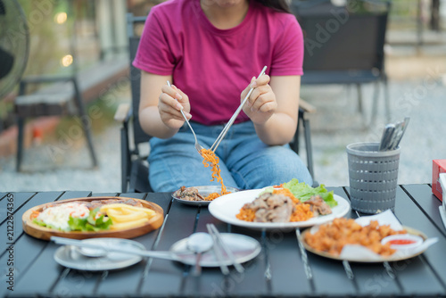 Woman eating a delicious meal at an outdoor restaurant with rice and meat dishes