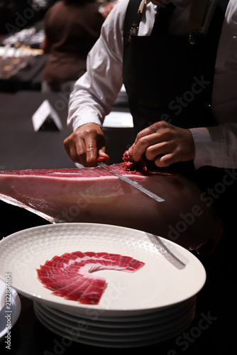 profesional charcutero sirviendo y cortando lonchas de jamón ibérico