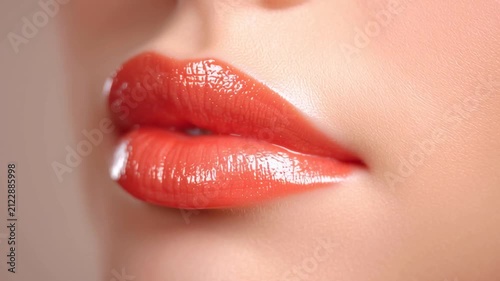Slow motion close up tracking shot of woman lips parting and glossy lipstick reflection in beauty studio portrait