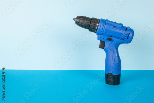 Obraz na plátne Blue Cordless Drill on Minimalist Blue Background: Modern Power Tool Design