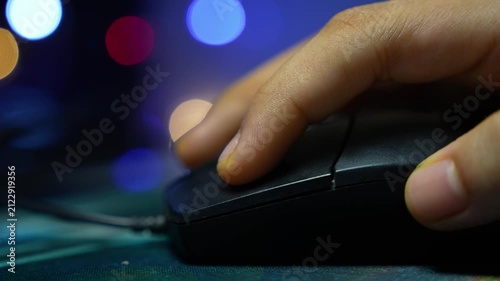 Close up of a hand using a computer mouse with blurred colorful lights in the background