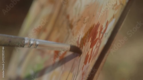 Close-up, artist's brush paints a forest landscape with watercolor