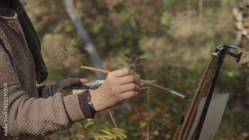 The artist paints a landscape of an autumn forest with watercolor on a sunny day