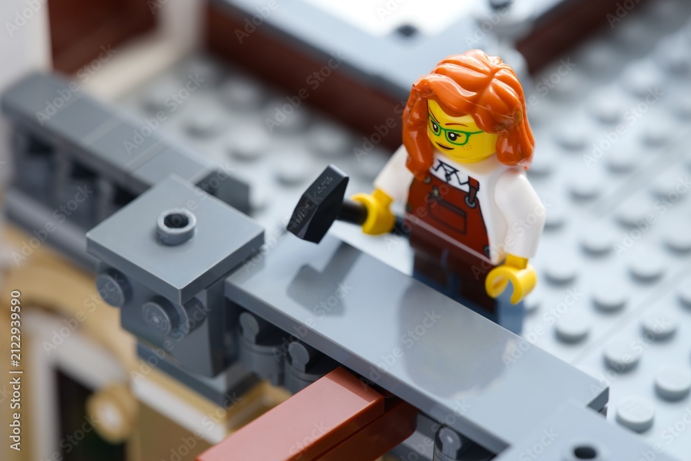 Fototapeta premium Tambov, Russian Federation - June 24, 2026 A Lego redhair woman minifigure with a hammer in a gray building. Close-up