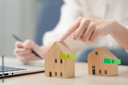 Home comparison concept. Person comparing two house models to choose the best property while planning a purchase. Real estate, home buying, comparison, property, investment