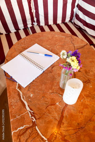 Notebook and flowers on marble cafe table with candle