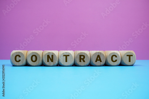 CONTRACT alphabet letters wooden cube with alarm clock on pink and blue background