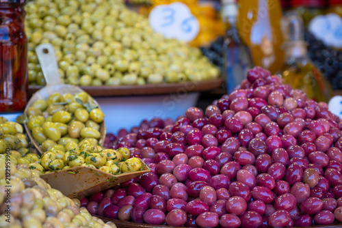 Colorful assortment of fresh green and purple olives displayed at a traditional market stall with shallow depth of field showcasing Mediterranean food culture and local culinary heritage