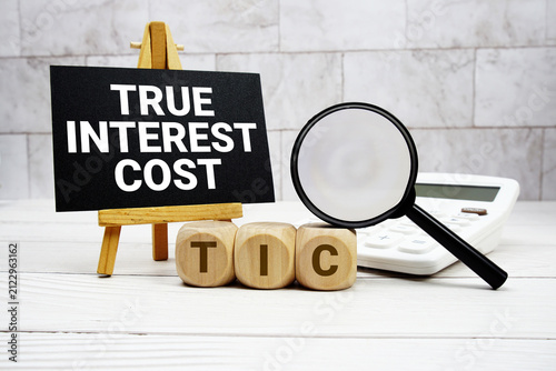 Принти на полотні TIC True Interest Cost text with calculator magnifying glass and on wooden backg