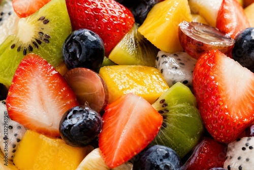 Macro close-up of a fresh glossy fruit salad with juicy tropical fruits and berries, vibrant healthy food background
