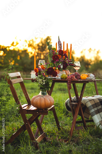 Fall table decoration with pumpkin composition. Family cozy thanksgiving dinner arrangement outdoors, in a garden, elegant wedding decor. Countryside style, rose wine, cheeseboard, fruits, autumn mood