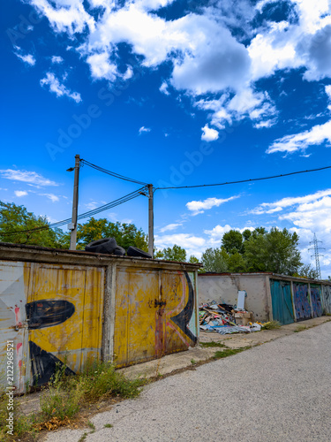 Foto Weathered garages and waste pile near utility poles
