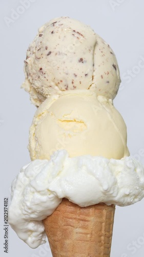 4K Vertical Close-up view of tree scoop ice cream with whipped cream on crispy waffle cone against plain background, Concept for summer dessert sweet treat dairy product and food background.