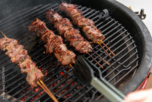 grilled meat skewers cooking on ceramic kamado barbecue grill