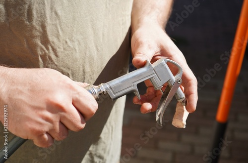 Foto Close-up of hands using a pneumatic air blow gun connected to an air compressor during vehicle maintenance