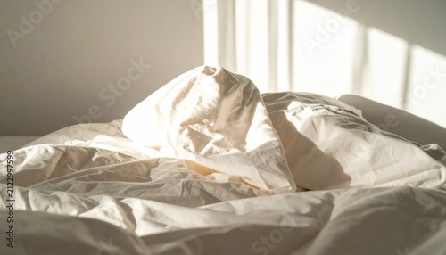 Unmade White Bedding Glowing in Warm Sunlight on Minimal Bedroom Bed