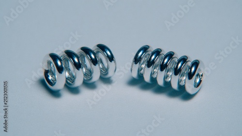 Two shiny metallic springs isolated on a clean, neutral background for industrial applications