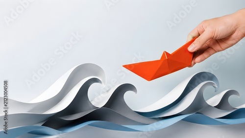 Hand holding an orange origami paper boat over layered paper waves representing rescue leadership and navigating through rough business seas