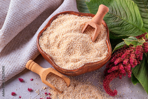 Amaranth grits in a wooden bowl with blooming branch amaranth, closeup with selective focus, top view